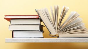 Books stacked and open, illustrating present indefinite tense examples and exercises for language learners.