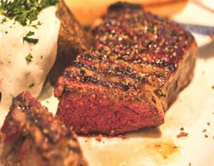 Grilled steak and fried eggs with a side of tomatoes