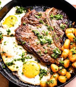 A customizable breakfast bowl with steak, scrambled eggs, spinach, and avocado.