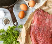 A close-up of a perfectly seared steak with grill marks next to a golden fried egg.