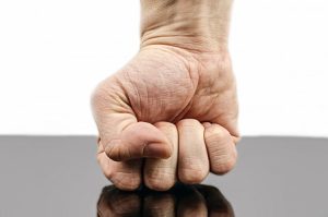A powerful clenched fist pointing downward, symbolizing the decisive elimination of common mistakes in present indefinite tense.