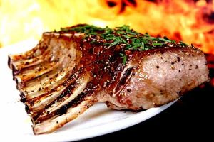 Close-up of a hot, perfectly seared Tomahawk Steak on Big Green Egg grill grates, showcasing a rich, dark crust and tender, juicy interior.