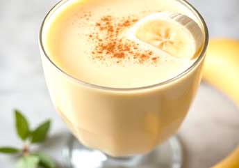 Banana oat breakfast smoothie in glass with rolled oats topping. Smoothies for Braces