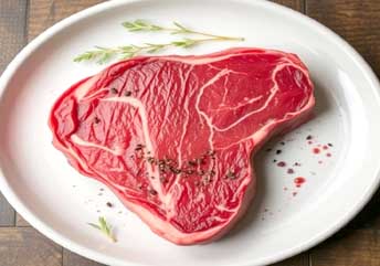 Close-up of fresh red steak next to spoiled steak with grayish-green discoloration and slimy texture, highlighting visual signs of steak spoilage for food safety.