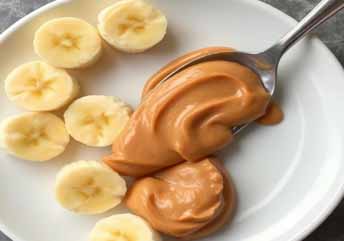 Spoonful of creamy peanut butter beside sliced banana — a soft, braces-friendly snack with smooth textures and natural sweetness. what foods can you eat with braces