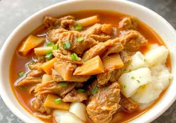 Soft shredded meat stew with mashed potatoes — a hearty, braces-friendly lunch served in a cozy bowl. what foods can you eat with braces