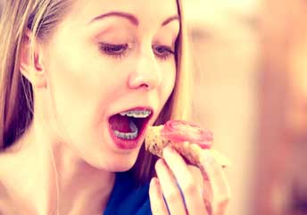 Happy female eating grilled chicken and vegetables as part of a balanced, high-protein diet.