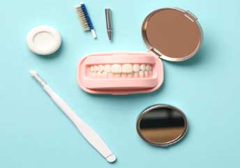 Flat lay of a portable braces-cleaning kit featuring a flosser, soft-bristle brush, and mini mirror, essential for maintaining oral hygiene after meals for braces, on a clean white background.