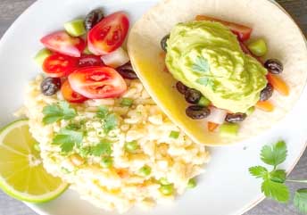 Close-up of a creamy soft risotto bowl paired with a taco topped with smooth mashed avocado spread, ideal for braces-friendly meals, served on a colorful plate with a spoon.