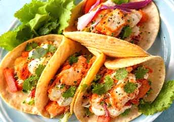 Side-by-side comparison of Ahi Tuna and Mahi Mahi tacos with colorful toppings on a wooden board