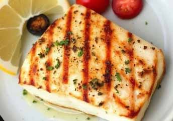 Grilled Mahi Mahi fillet served with lemon wedges and fresh herbs on a rustic plate