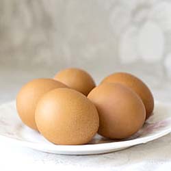 Five poached eggs on a bed of fresh greens highlighting the nutrient density and Calories in 5 eggs.