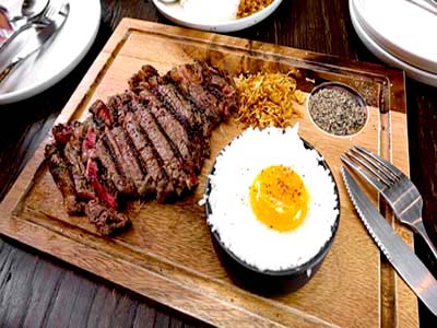 Top-down view of a juicy ribeye steak and sunny-side-up eggs on a plate for a steak and eggs carnivore diet.